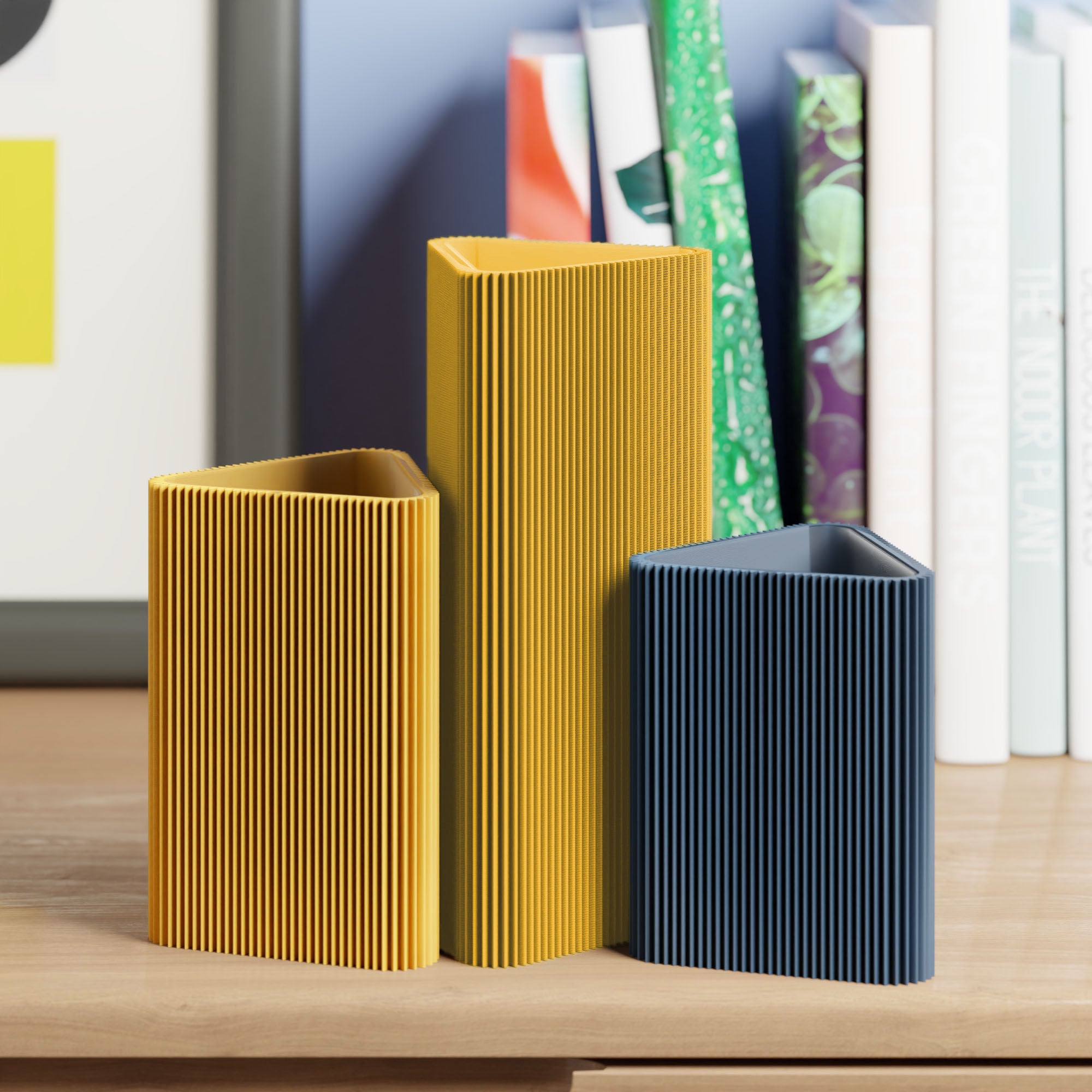Geometrische Vase DREIECK in senfgelb mit zwei weiteren Vasen vor Büchern im Regal #farbe_senfgelb