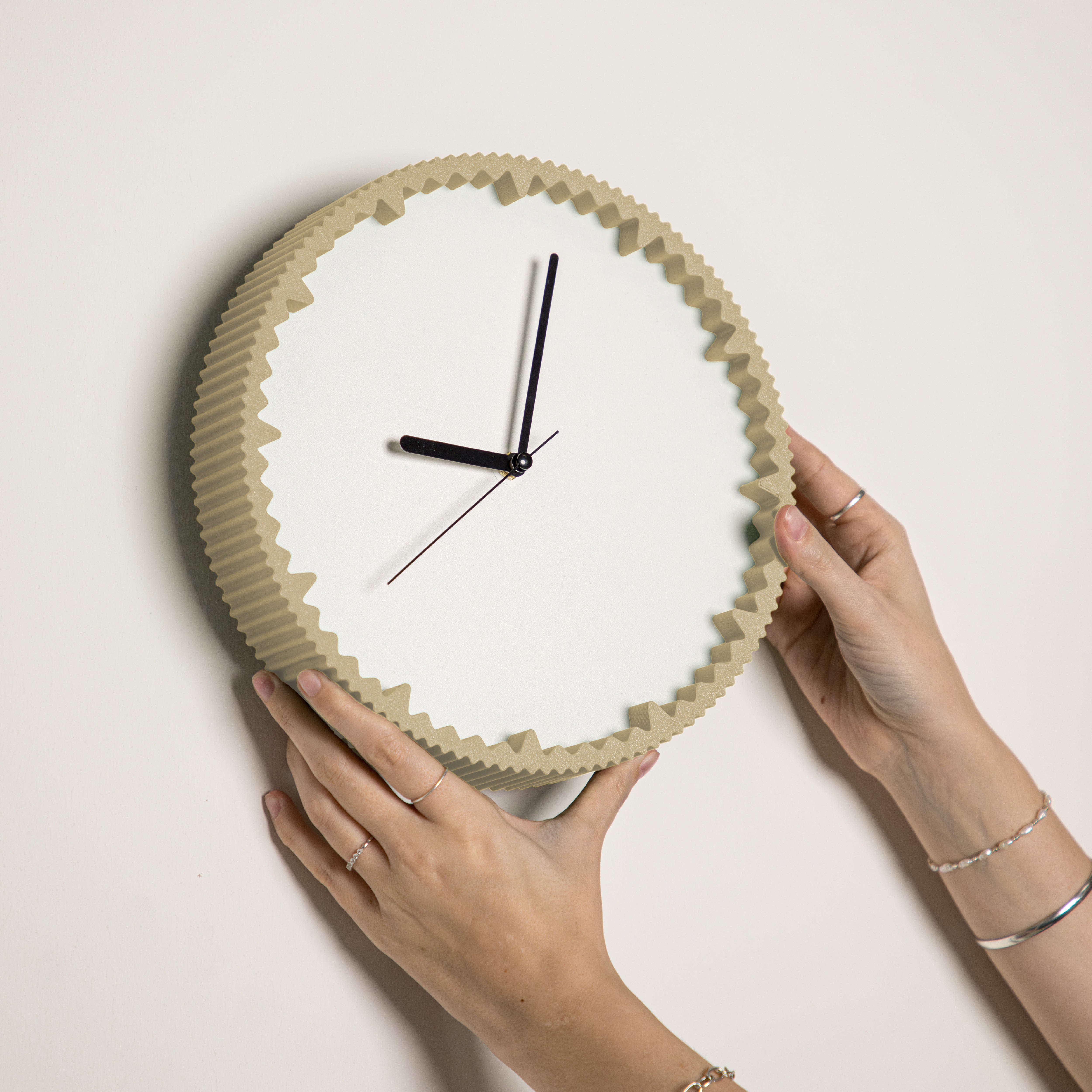 Hände hängen moderne Wanduhr beige mit gezacktem Rand aus dem 3D Druck an die Wand #farbe_beige