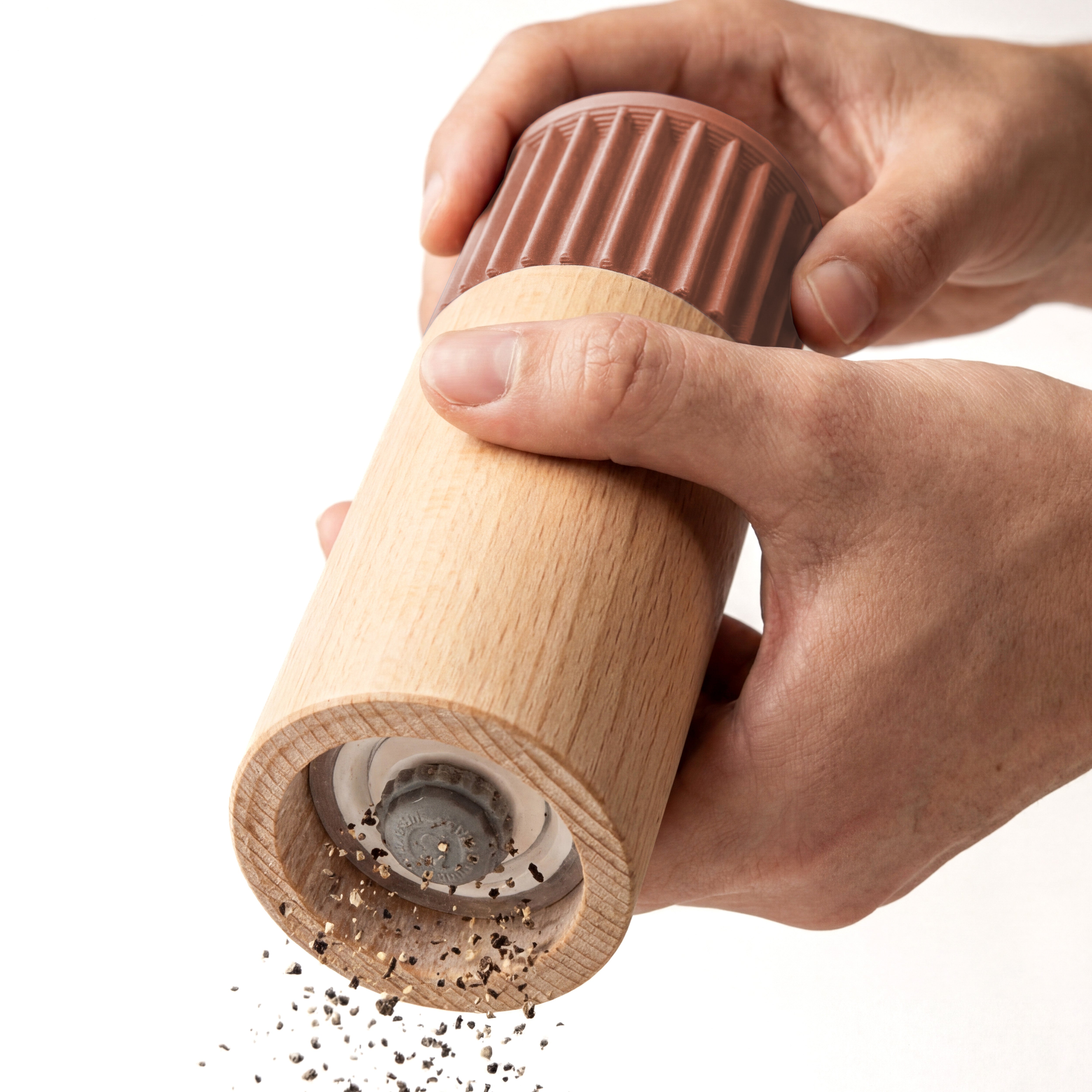 Hände mahlen Pfeffer mit der Gewürzmühle Prise in terracotta aus Buchenholz vor weißem Grund #farbe_terracotta