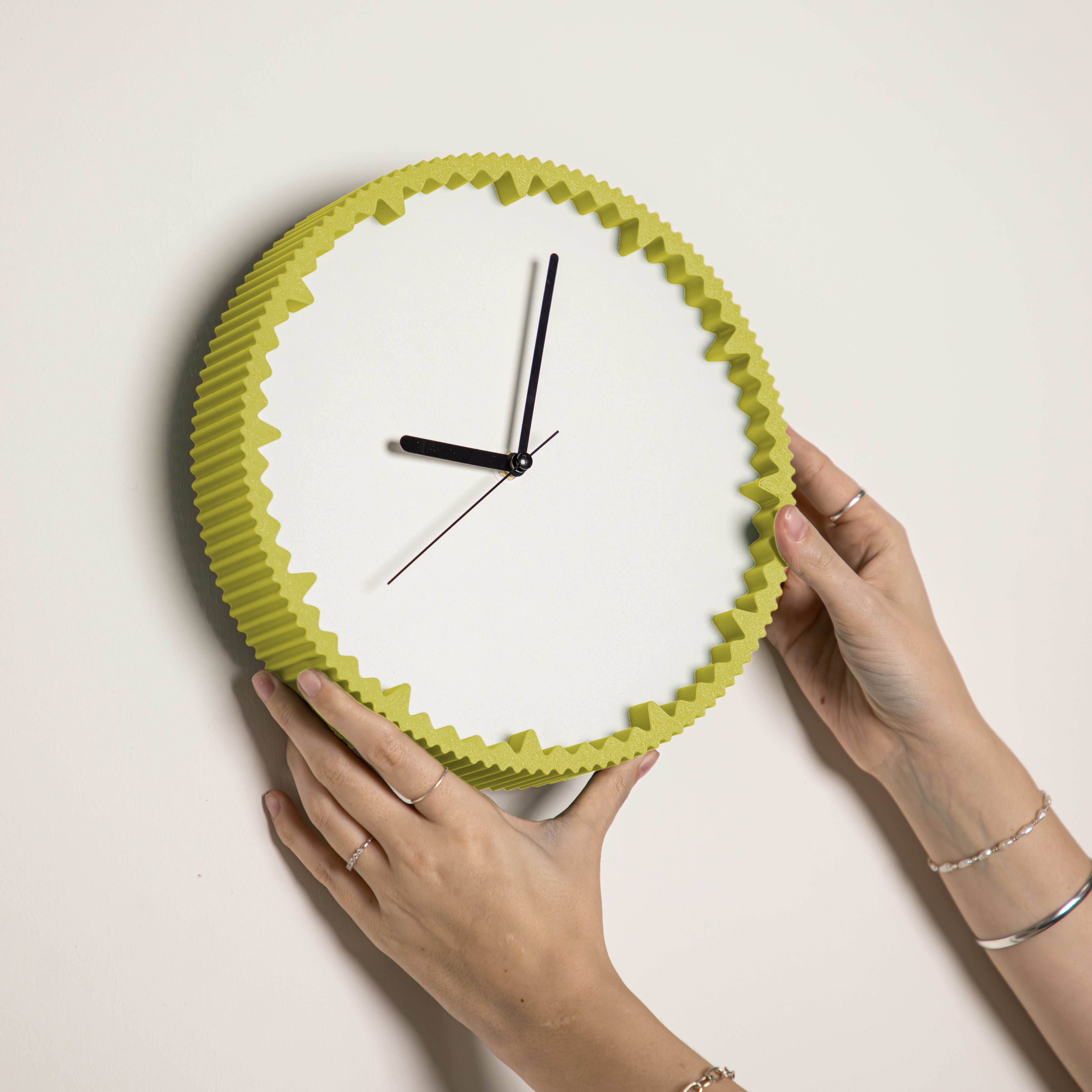 Hände hängen moderne gelb Wanduhr mit gezacktem Rand aus dem 3D Druck an die Wand #farbe_gelb