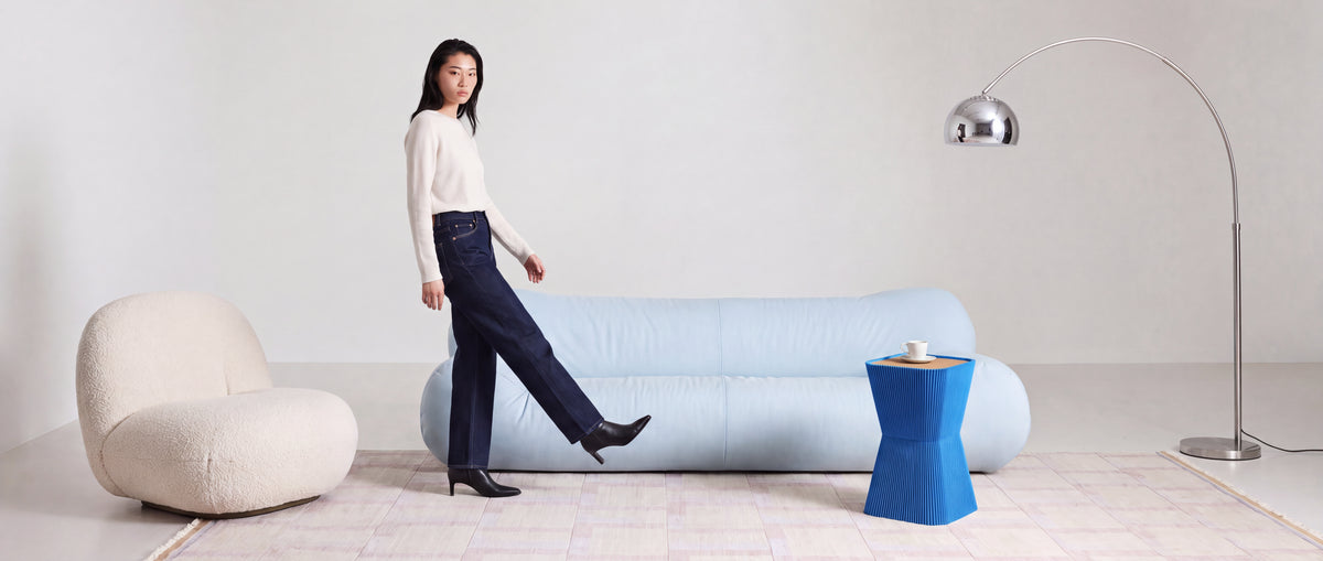 Blauer Beistelltisch PYRAMIDE aus 3D Druck mit Rillenstruktur und Holzplatte neben hellblauem Sofa